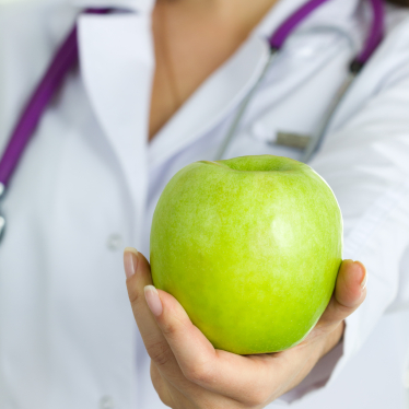 Close up view of medical doctor hand offering green apple